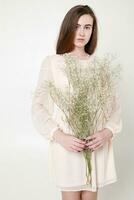 gekruld romantisch Look, mooi ogen. wit wilde bloemen in handen. foto