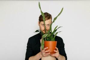 een jong glimlachen Mens houdt in zijn handen een klein bloem foto