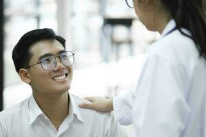een gelukkig jong is glimlachen terwijl zijn dokter is ondersteuning hem. foto