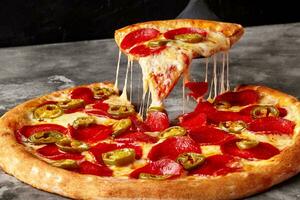 plak van pizza met gesmolten Mozzarella, peperoni en jalapeno Aan portie spatel foto