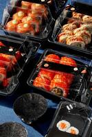 reeks van sushi broodjes Ingepakt in plastic meenemen containers met gember en soja saus foto