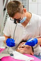 tandarts in de kliniek, procedure voor het verwijderen van tandsteen. foto