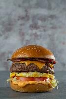 eigengemaakt Hamburger met rundvlees, tomaat, ui en kaas Aan grijs achtergrond foto