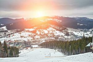 panorama van ski toevlucht, helling, mensen Aan de ski tillen, skiërs Aan de piste tussen groen pijnboom bomen en sneeuw lansen. foto