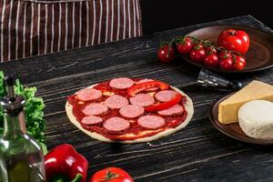 koken in de keuken zetten de ingrediënten Aan de pizza. pizza concept. productie en levering van voedsel. foto
