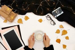 vrouwen handen houden een kop van koffie, sjaal Aan wit achtergrond. herfst of winter concept. vlak leggen, top visie foto