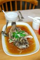 stoom- gebakken gemarmerd goby vis gebeld ikan mala's in Siamees stijl geserveerd in een schotel Aan een houten tafel in een restaurant in Indonesië foto