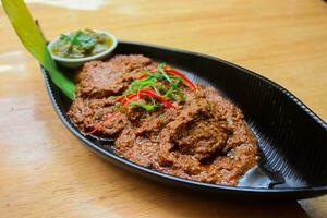 rundvlees rendang is een minang schotel afkomstig van de minangkabau regio in west sumatra, Indonesië. rendang heeft geweest langzaam gekookt en gestoofd in een kokosnoot melk gekruid met een kruid en kruid mengsel foto