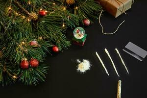 cocaïne verdeeld in paden met Kerstmis speelgoed en net Afdeling Aan zwart achtergrond top visie. foto