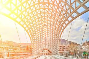 de brug van vrede is voetganger brug over- de kura rivier- in tbilisi, hoofdstad van Georgië. zon gloed foto