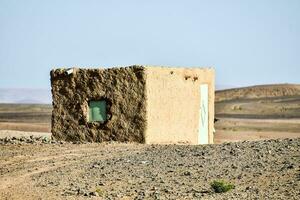 een klein huis in de woestijn met een groen venster foto