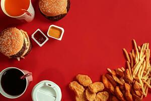 snel voedsel schotel top visie. vlees hamburger, aardappel chips en glas van drinken Aan rood achtergrond. meenemen samenstelling. foto