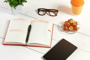 elegant minimalistisch werkplaats met tablet en notitieboekje en bril in vlak leggen stijl. wit achtergrond. foto