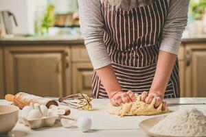 vrouw handen kneden deeg Aan keuken tafel foto