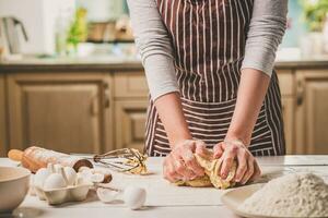 vrouw handen kneden deeg Aan keuken tafel foto