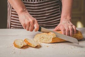 vrouw snijdend brood Aan houten bord. bakkerij. brood productie. foto