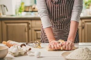 vrouw handen kneden deeg Aan keuken tafel foto