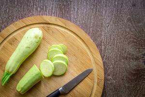 een gesneden courgette Aan een houten bord. houten achtergrond foto