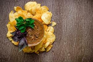 aardappel chips met dompelen saus Aan een houten tafel. ongezond voedsel Aan een houten achtergrond. foto