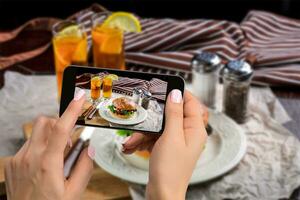 een jong vrouw nemen foto van voedsel Aan smartphone, fotograferen maaltijd met mobiel camera