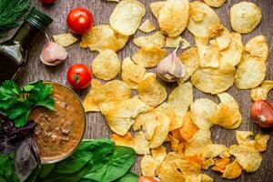 aardappel chips met dompelen saus Aan een houten tafel. ongezond voedsel Aan een houten achtergrond. foto