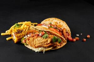 taco's met kip, tomaat en vers groenten en tandsteen saus Aan zwart achtergrond foto