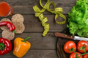 sport en eetpatroon. groenten, een glas van tomaat sap en centimeter. pepers, tomaten, salade Aan rustiek achtergrond foto
