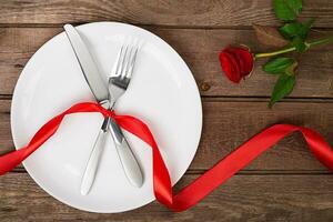 valentijnsdag dag tafel instelling met bord, vork, mes, lint en roos. achtergrond foto