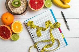 gezond ontbijt met havermout, vers fruit en notitieboekje Aan rustiek houten tafel. foto