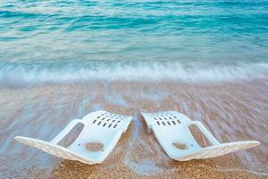 landschap van twee eenzaam strandstoelen in de buurt de zee foto