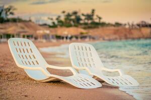 landschap van twee eenzaam strandstoelen in de buurt de zee foto
