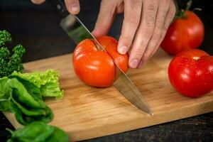 mannetje handen snijdend groenten voor salade foto