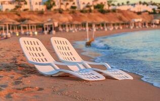 landschap van twee eenzaam strandstoelen in de buurt zee en mooi zonsopkomst foto
