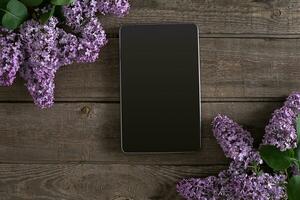 lila bloesem Aan rustiek houten achtergrond, tablet met leeg ruimte voor groet bericht. top visie foto