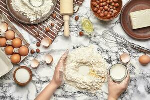 detailopname schot. top visie van een bakker koken plaats, handen zijn werken met een rauw deeg Aan de marmeren tafel achtergrond. foto