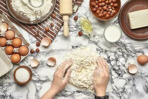 detailopname schot. top visie van een bakker koken plaats, handen zijn werken met een rauw deeg Aan de marmeren tafel achtergrond. foto