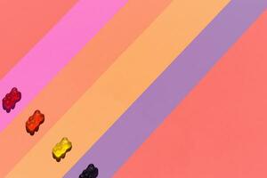 kleurrijk gelei bonen bears geplaatst Aan gestreept gekleurde pastel. elk beer Aan haar eigen strip foto