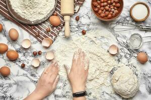 detailopname schot. top visie van een bakker koken plaats, handen zijn werken met een rauw deeg Aan de marmeren tafel achtergrond. foto