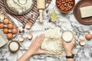 detailopname schot. top visie van een bakker koken plaats, handen zijn werken met een rauw deeg Aan de marmeren tafel achtergrond. foto