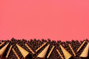 chocola dragee en wafel kegels geplaatst in fascinerend bestellen Aan koraal achtergrond, visie van bovenstaand foto