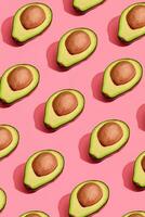 kleurrijk fruit patroon van vers gesneden avocado helften met kuilen Aan koraal roze achtergrond, top visie foto