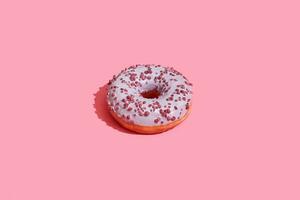voedsel ontwerp. dichtbij omhoog hoog kwaliteit beeld van roze geglazuurd donut Aan koraal roze achtergrond foto