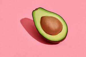 kleurrijk fruit patroon van vers gesneden avocado halveren met pit Aan koraal roze achtergrond, top visie foto