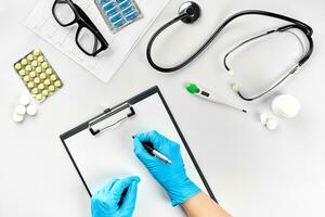 vrouw dokter hand- in blauw handschoenen vulling de medisch Vermelding Aan wit tafel foto