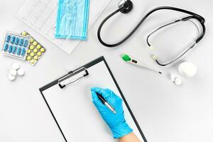 vrouw dokter hand- in blauw handschoenen vulling de medisch Vermelding Aan wit tafel foto