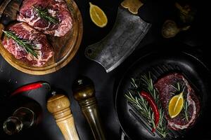 vers rauw vlees. rundvlees lende en gemarmerd rundvlees steaks Aan rooster pan en frituren bord met kruiden, zwart achtergrond top visie. foto