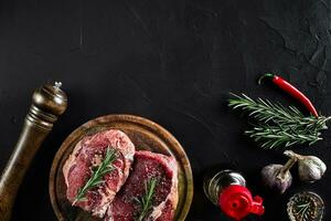 rauw rundvlees steak met specerijen en ingrediënten voor Koken Aan snijdend bord en leisteen achtergrond. top visie. foto
