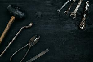oud, roestig gereedschap aan het liegen Aan een zwart houten tafel. hamer, beitel, metaal schaar, moersleutel. foto