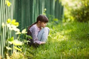 verdrietig meisje zittend op het gras foto