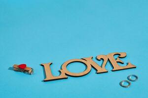 houten opschrift liefde en de ring Aan blauw achtergrond. huwelijk voorstel. de concept van Valentijnsdag dag foto